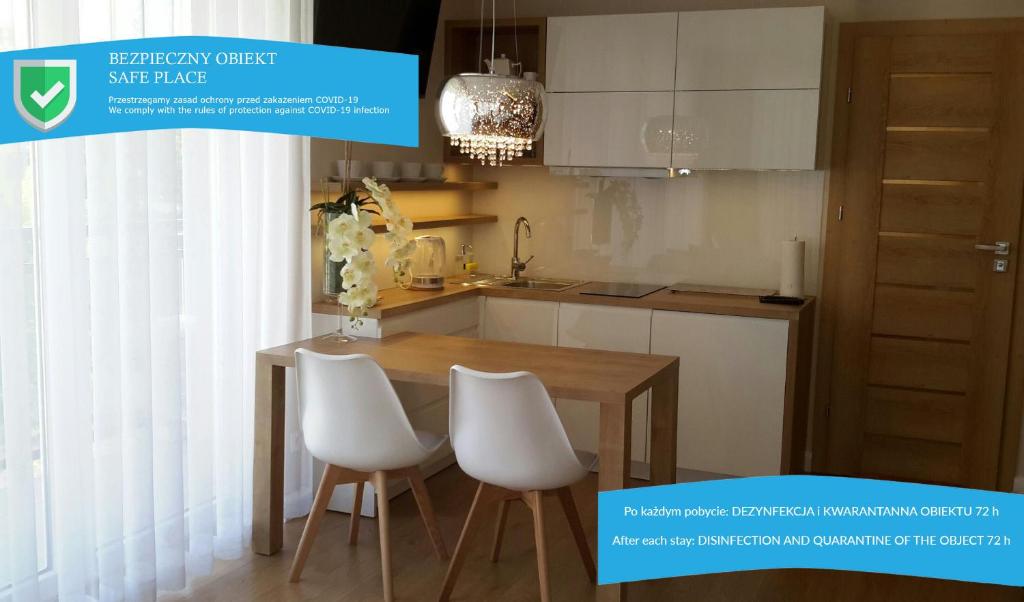 a kitchen with a wooden table and white chairs at Apartament Aria Studio in Krakow