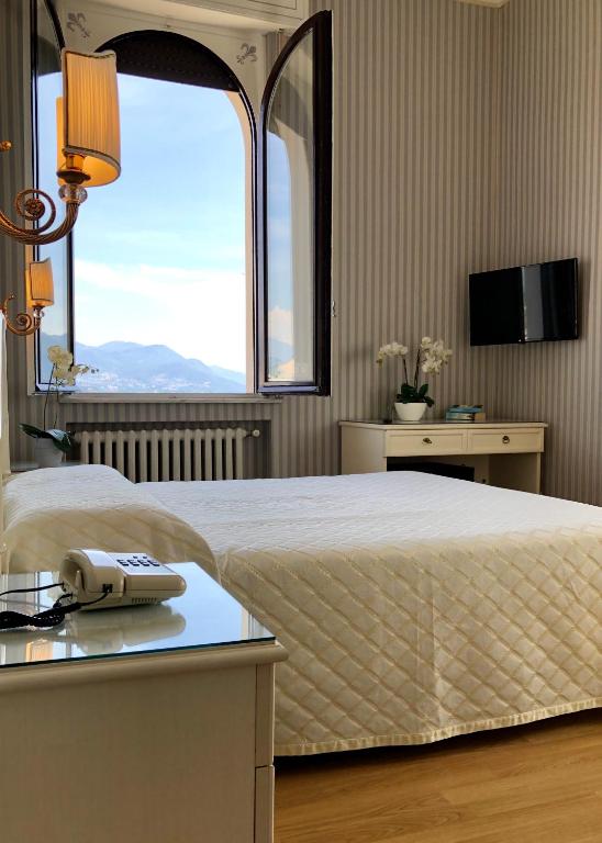 a bedroom with a bed with a phone on a table at Hotel Du Parc in Stresa