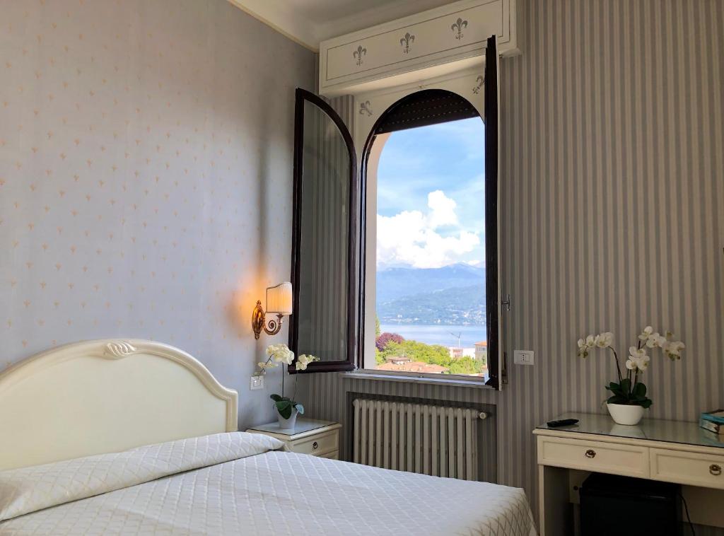 a bedroom with a bed and a large window at Hotel Du Parc in Stresa