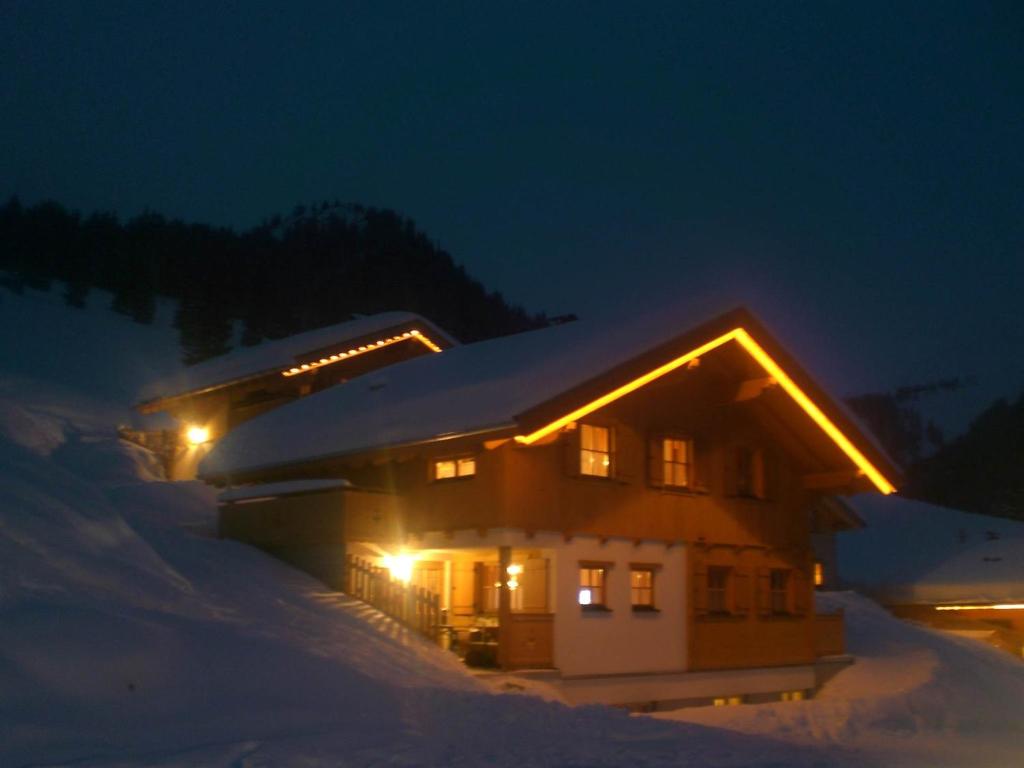 una casa cubierta de nieve por la noche con luces en Dreimäderlhaus en Sankt Gallenkirch