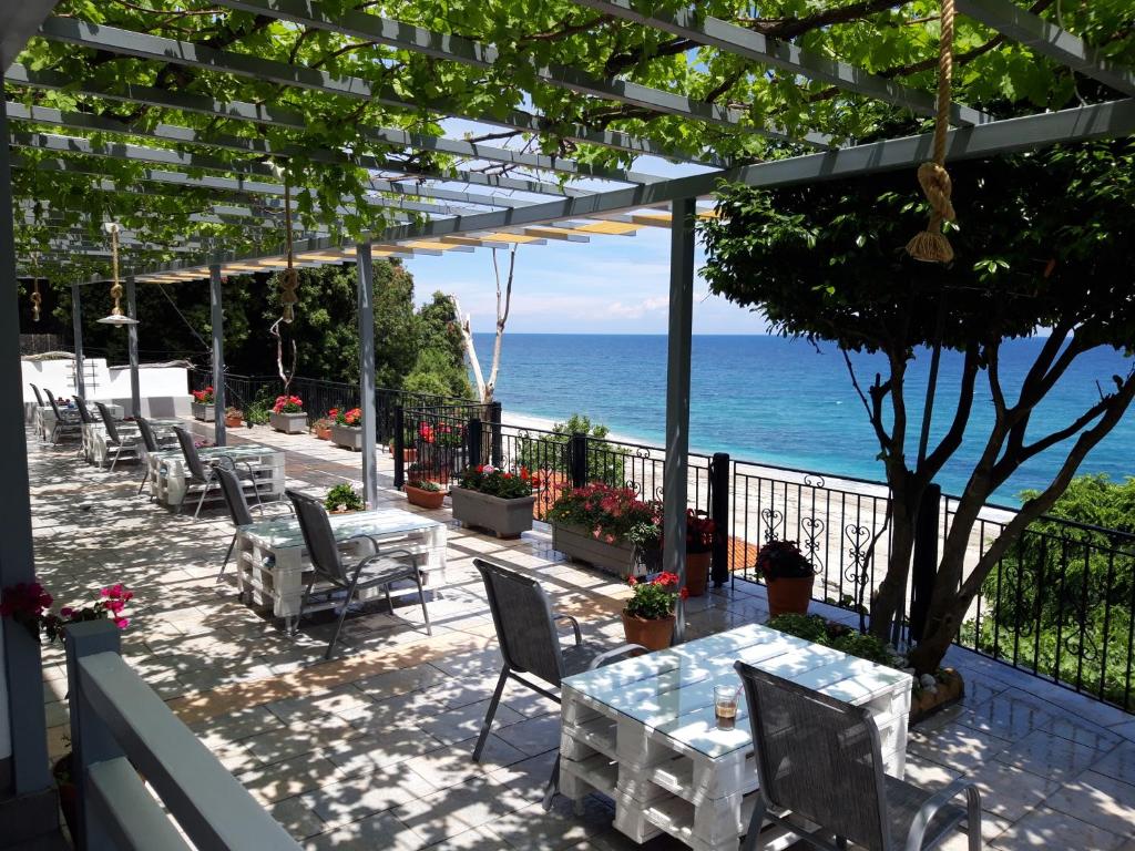 um pátio com uma mesa e cadeiras e o oceano em Ammos papanero em Agios Ioannis Pelion