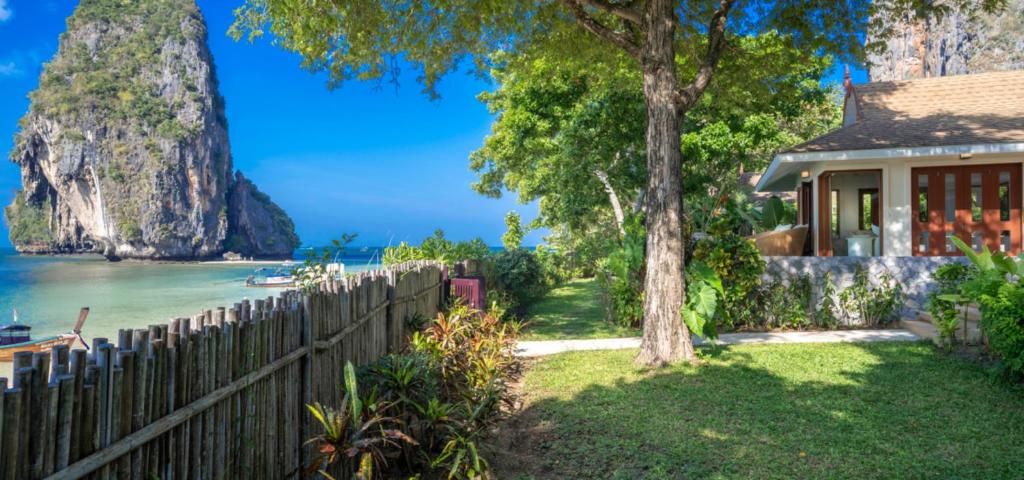 ein Haus mit einem Zaun, einem Baum und dem Meer in der Unterkunft Villa Macaque and Villa Languor in Railay Beach