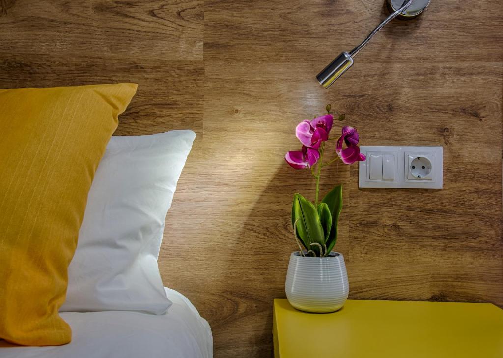 a vase with flowers on a table next to a bed at Hostal-Restaurante LUGANO in Verín