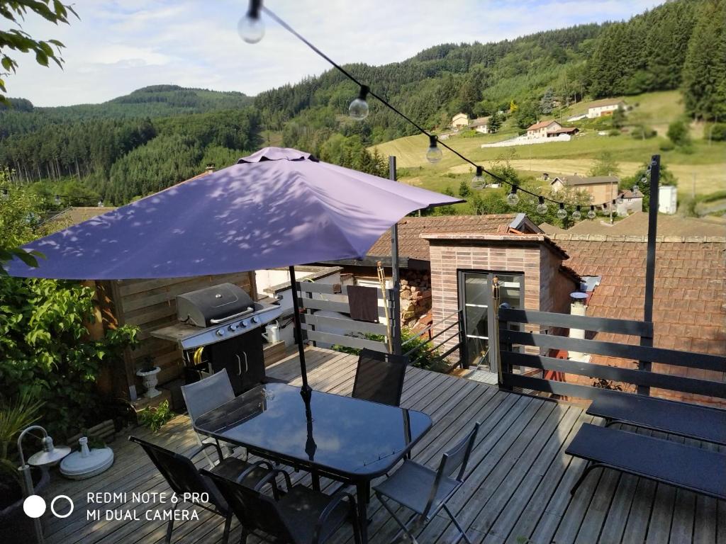 een tafel met een paraplu op een terras met een grill bij lesfilatures in Saint-Vincent-de-Reins