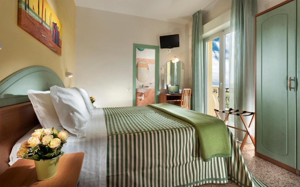 een slaapkamer met een bed met een vaas met bloemen erop bij Hotel Caravel B&B in Misano Adriatico