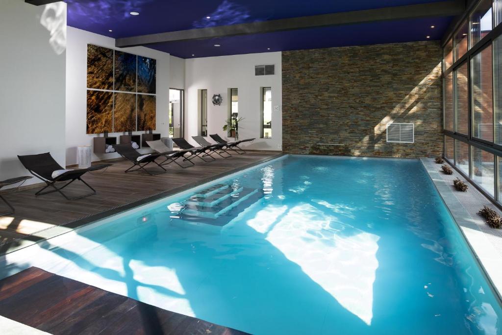 una gran piscina con sillas en una casa en Le Dracy Hôtel et Spa, en Dracy-le-Fort