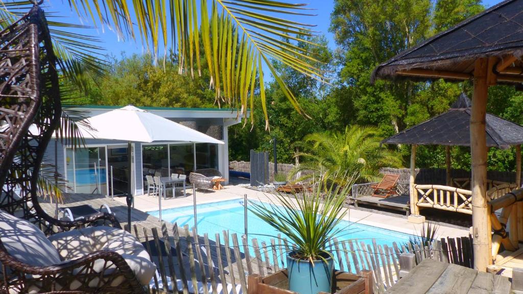 a swimming pool with chairs and an umbrella at Ohana Lodge in Moliets-et-Maa