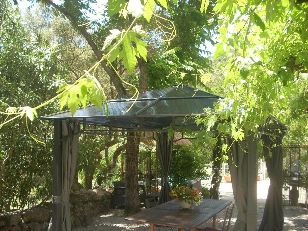 un pergolato con un tavolo da picnic sotto un albero di Demeure traditionnelle en pierre avec piscine a Sartène
