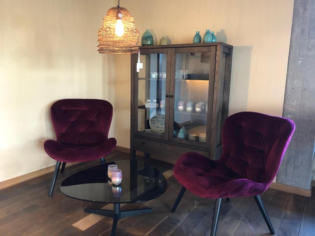 two red chairs and a glass table in a room at Hotel Kronenhof in Zurich