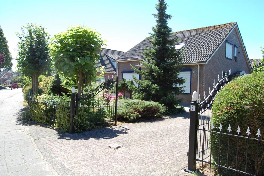 a fence in front of a house with a tree at B&B Gamerenwaard in Gameren