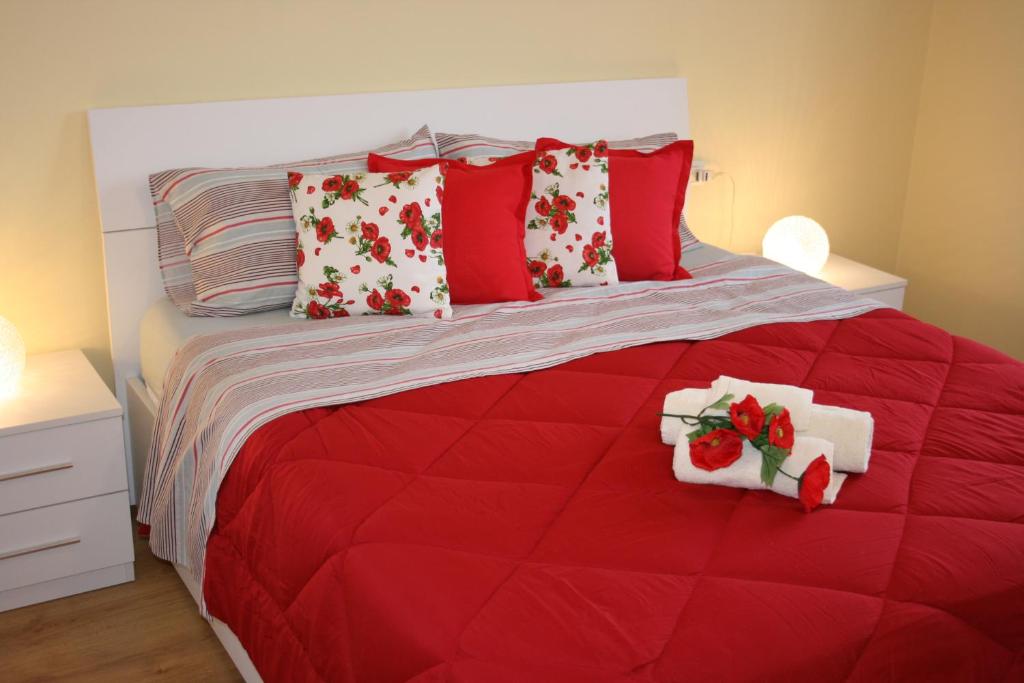 a red bed with red and white pillows on it at Le Margherite in Cardano al Campo