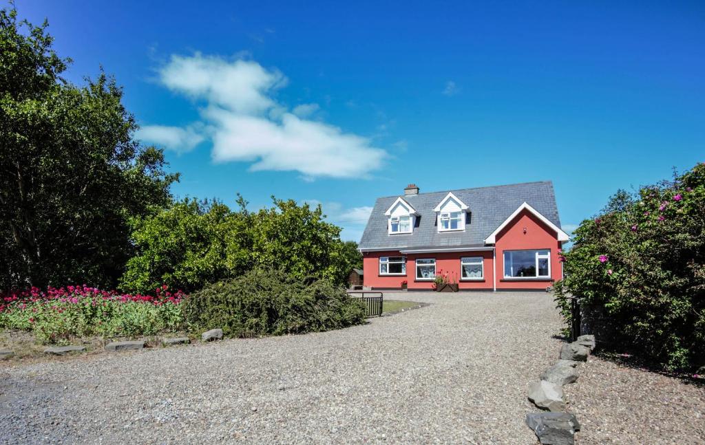 ein rotes und weißes Haus mit Kieseinfahrt in der Unterkunft BlueTit Lodge in Kilkee