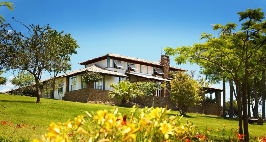 ein Haus auf einem Hügel mit Bäumen und Gras in der Unterkunft Lake Vilas Charm Hotel in Amparo