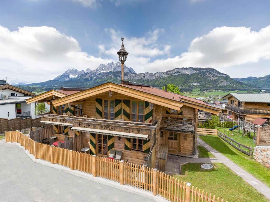 a large wooden building with mountains in the background at Chalets Berglehen in Sankt Johann in Tirol