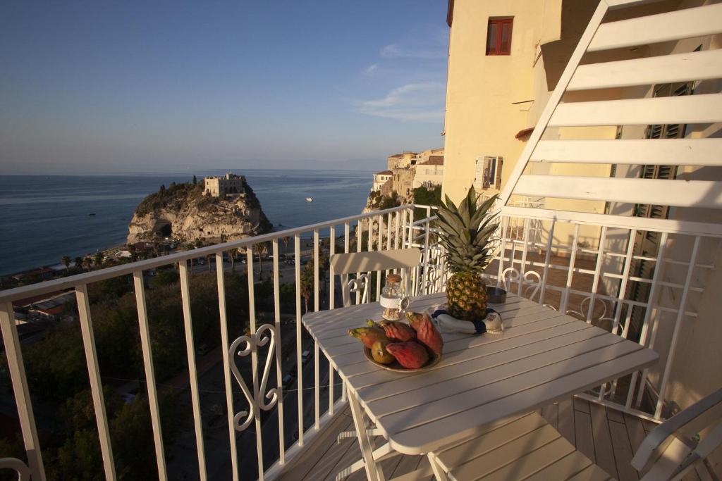 a table on a balcony with a view of the ocean at Le Tolde del Corallone in Tropea