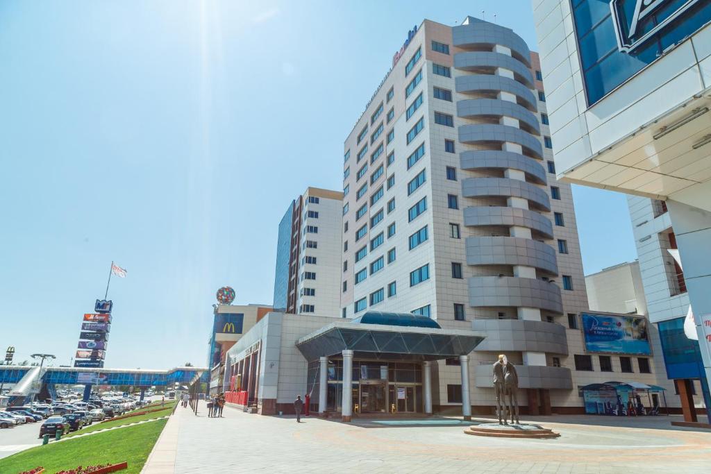 een hoog gebouw in een stad met een parkeerplaats bij GRINN HOTEL & SPA in Oryol
