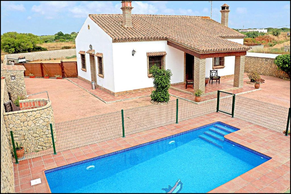 a house with a swimming pool in front of it at Chalet Puente de Tabla in Conil de la Frontera