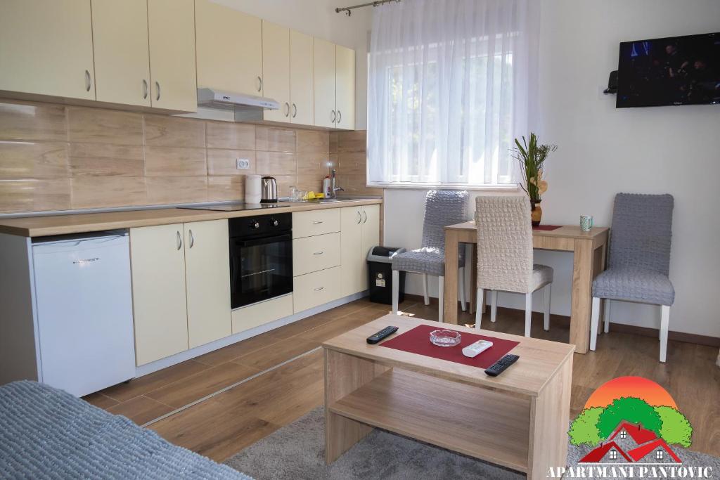 a kitchen with white cabinets and a table and chairs at Apartmani Pantovic - Apartman 1 in Trebinje