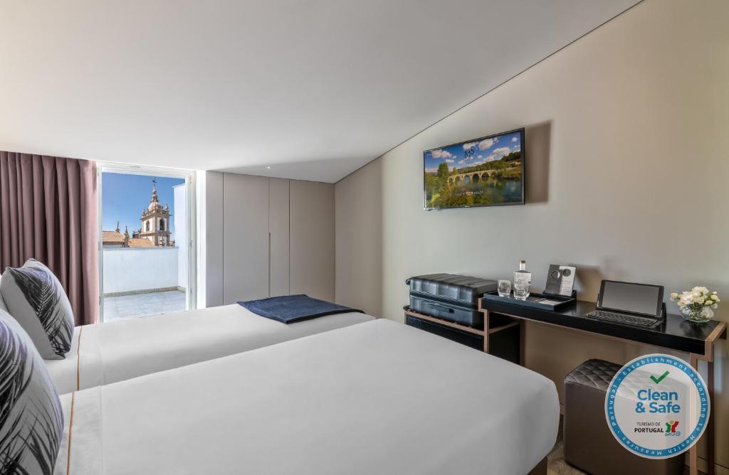 Hotel Moon & Sun Braga في براغا: غرفه فندقيه بسرير ومكتب ونافذه