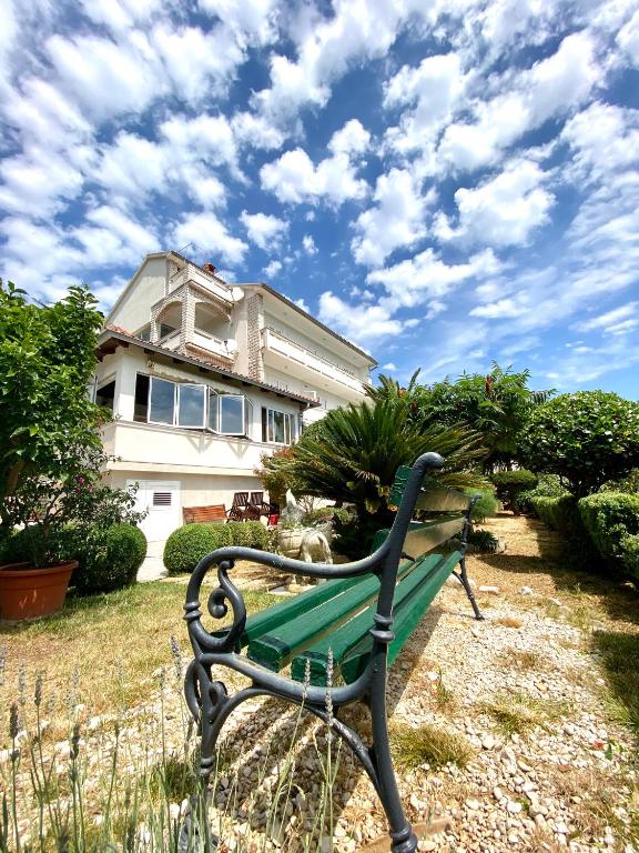 a green park bench in front of a house at Guesthouse Kurelic Rab in Kampor