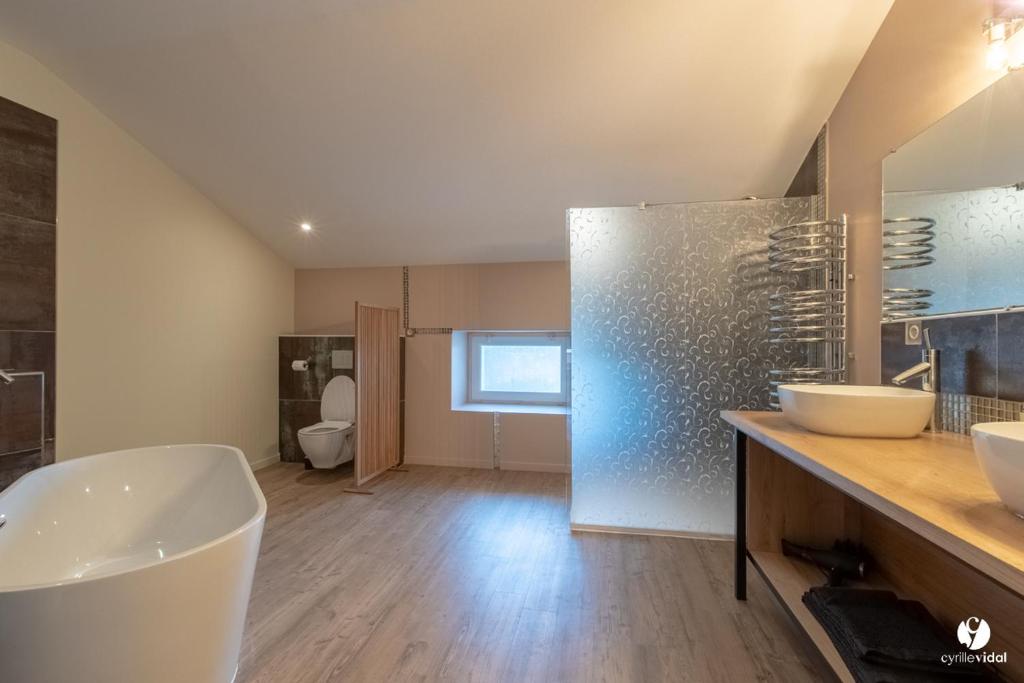 a bathroom with a tub and two sinks and a toilet at Othil in Aire-sur-lʼAdour