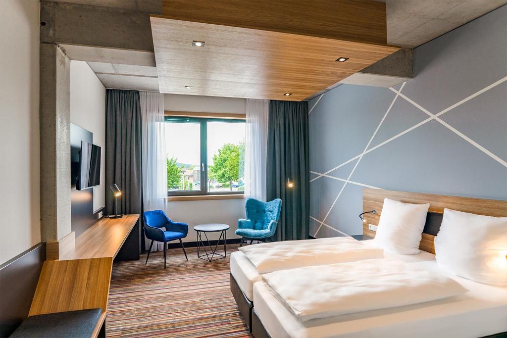 Cette chambre comprend un lit, un bureau et des chaises. dans l'établissement N+S City Hotel Neumarkt, à Neumarkt in der Oberpfalz