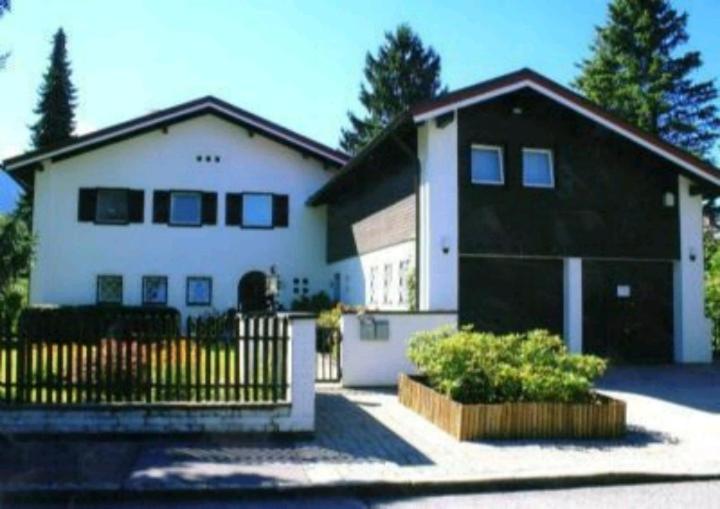 ein weißes und schwarzes Haus mit einem schwarzen Zaun in der Unterkunft Ferienwohnungen Sernatinger in Bad Reichenhall