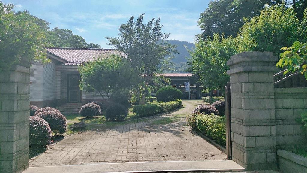a driveway leading to a house with a garden at 進泉莊民宿 有卡拉ok可以烤肉可以帶寵物 in Miaoli