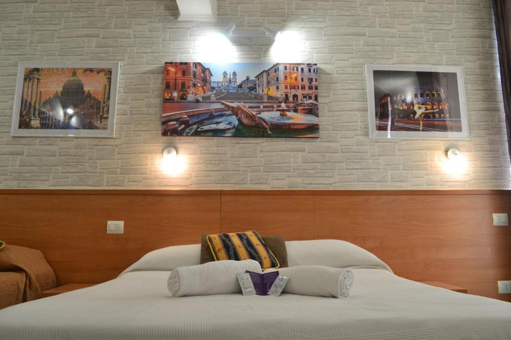 a bed in a room with three paintings on the wall at A&F Colosseo in Rome