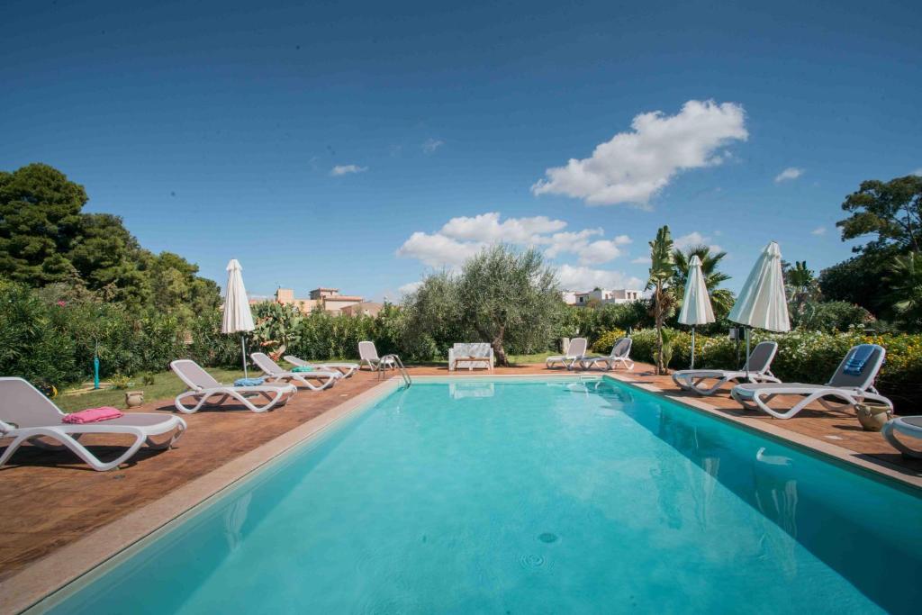 - une piscine avec des chaises longues et des parasols dans l'établissement Pietre Rosse Sicule - case vacanze Elena e Marta, à Montevago