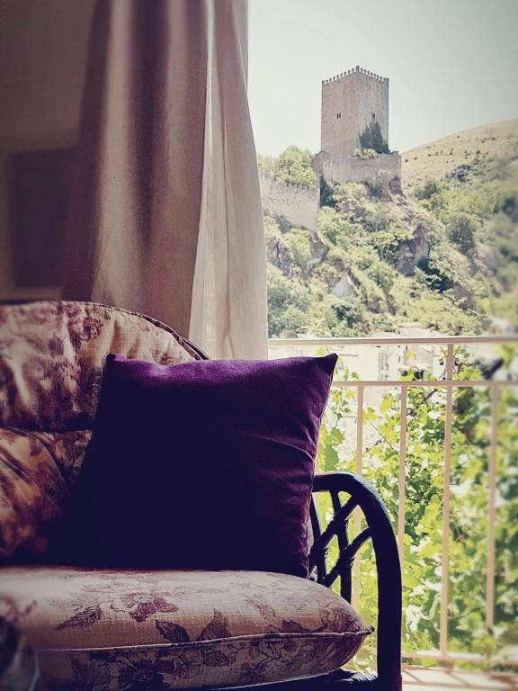 a pillow on a chair in front of a window with a castle at La Casa De Mariana in Cazorla
