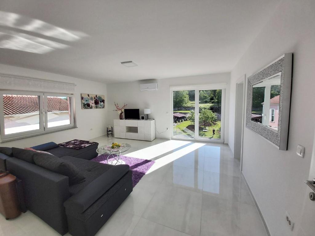 salon z czarną kanapą i oknami w obiekcie Comfortable apartment near Opatija w mieście Matulji