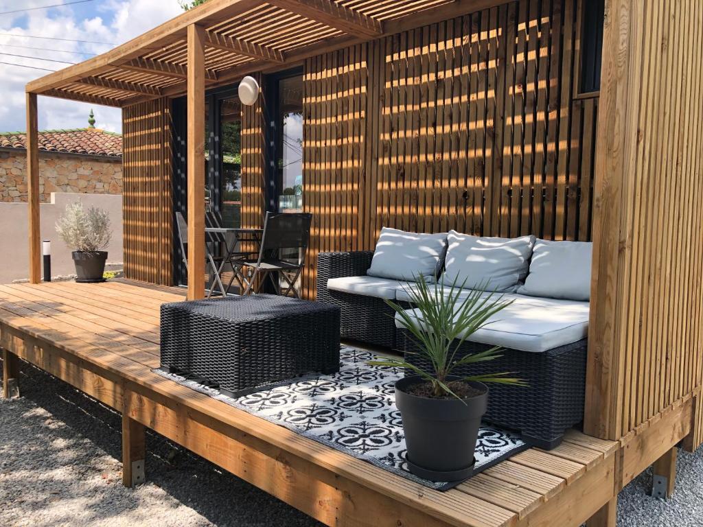 a wooden pergola with a couch and a plant on a deck at La Cabane in Draguignan