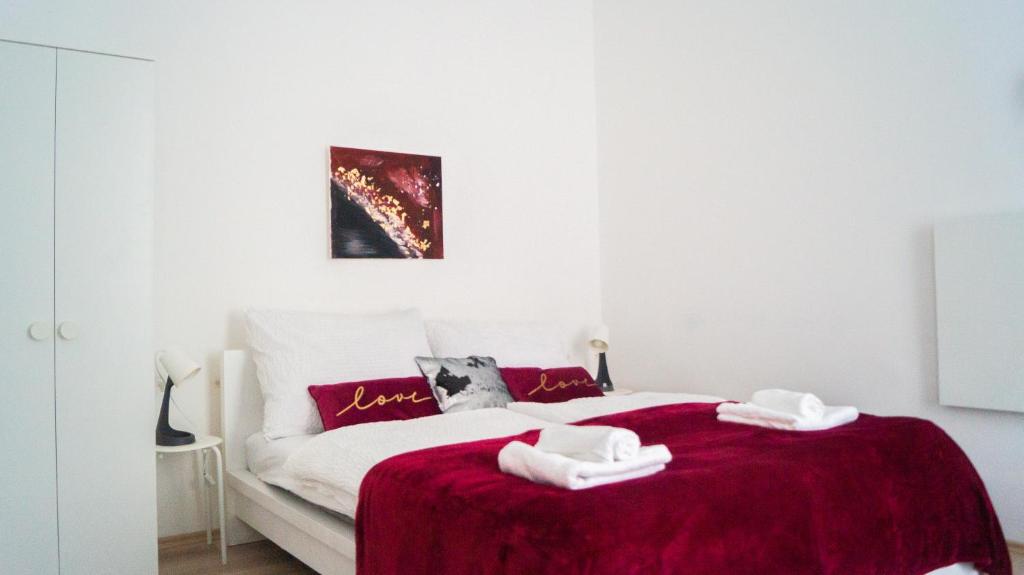 Un dormitorio con una cama roja y blanca con toallas. en Brilliant 1BR Apt - Perfect for Longstays, en Viena