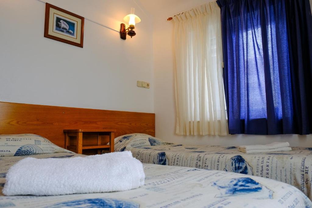 a bedroom with two beds and a window with blue curtains at Rimavier Residence in Peniche