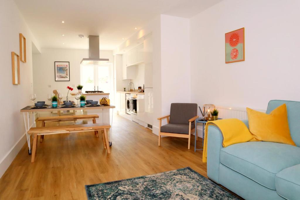 a living room with a blue couch and a table at Modern New House - Great Location - Garden - Parking - Fast WiFi - Smart TV - Stunning 2 Bedroom House sleeps up to 4! Only 5 mins drive to Sandbanks Beach in Parkstone