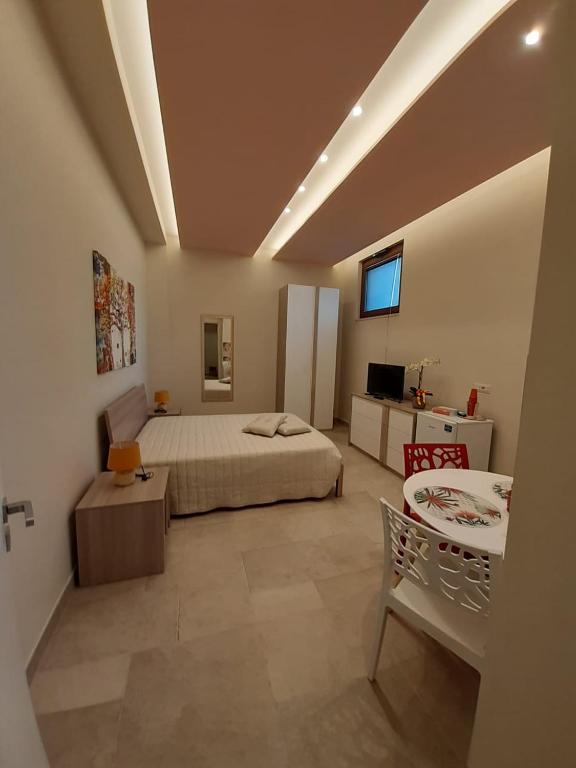 1 dormitorio con cama, mesa y TV en Casa Pompelmo Rosa, en Bernalda