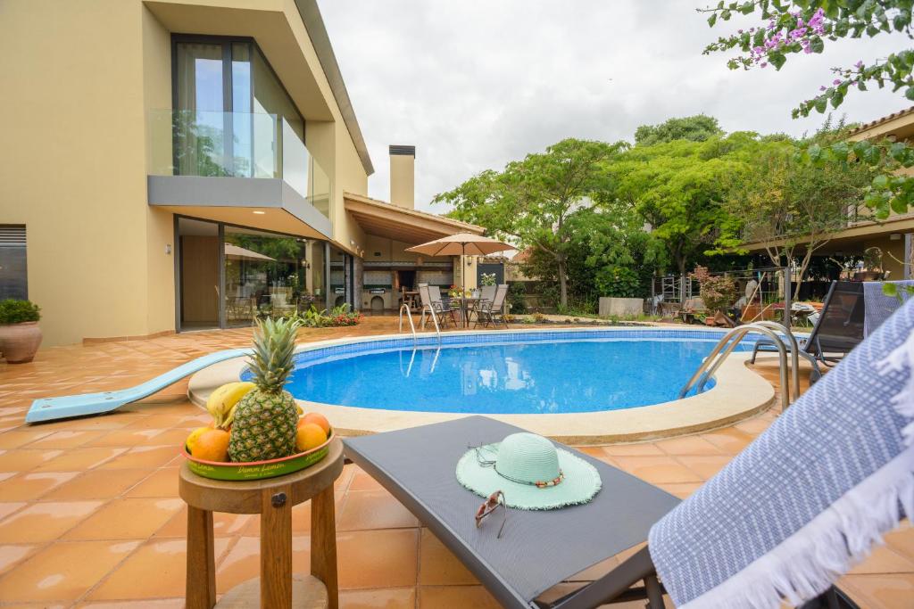 une villa avec une piscine et une table avec un ananas dans l'établissement Casa Deluxe Alt Empordà Costa Brava - Private swimming pool, à Vilabertrán