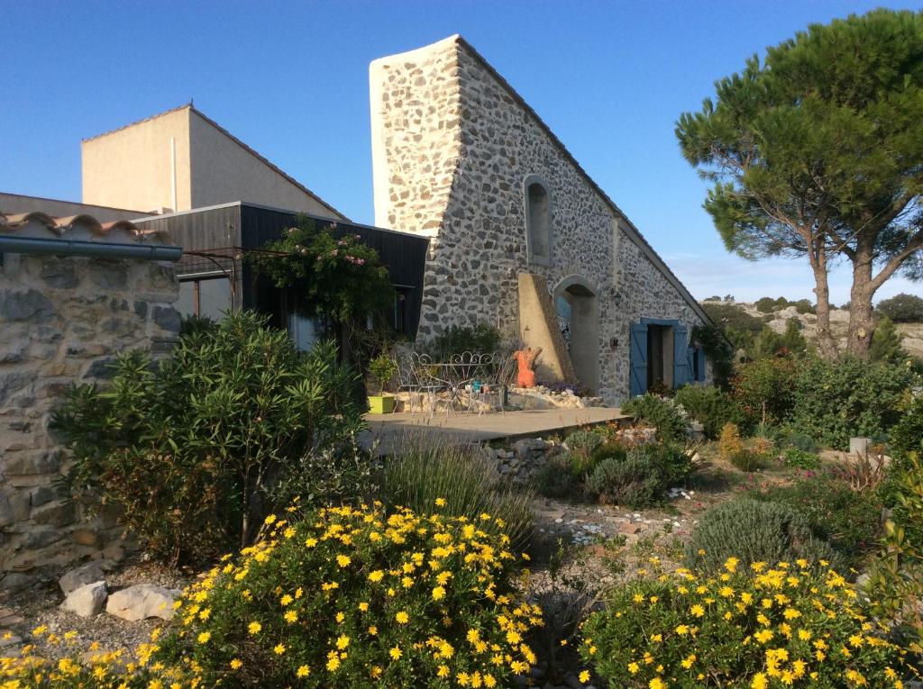 a stone house with a garden with yellow flowers at Domaine Castelsec in Roquefort-des-Corbières