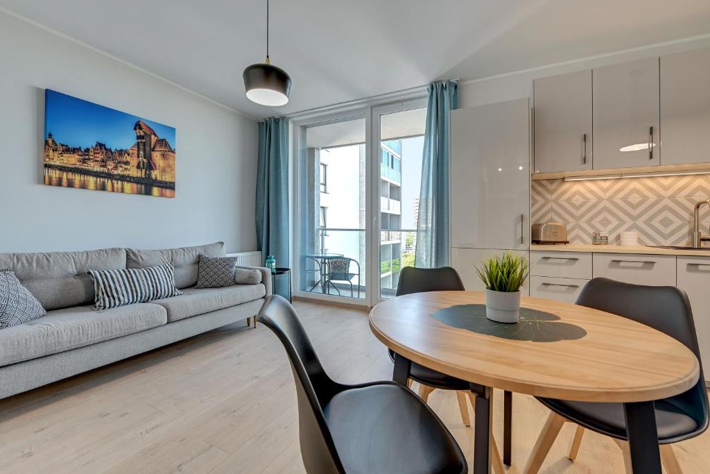 uma sala de estar com uma mesa e cadeiras e um sofá em Wave Apartments - SOLVO em Gdansk