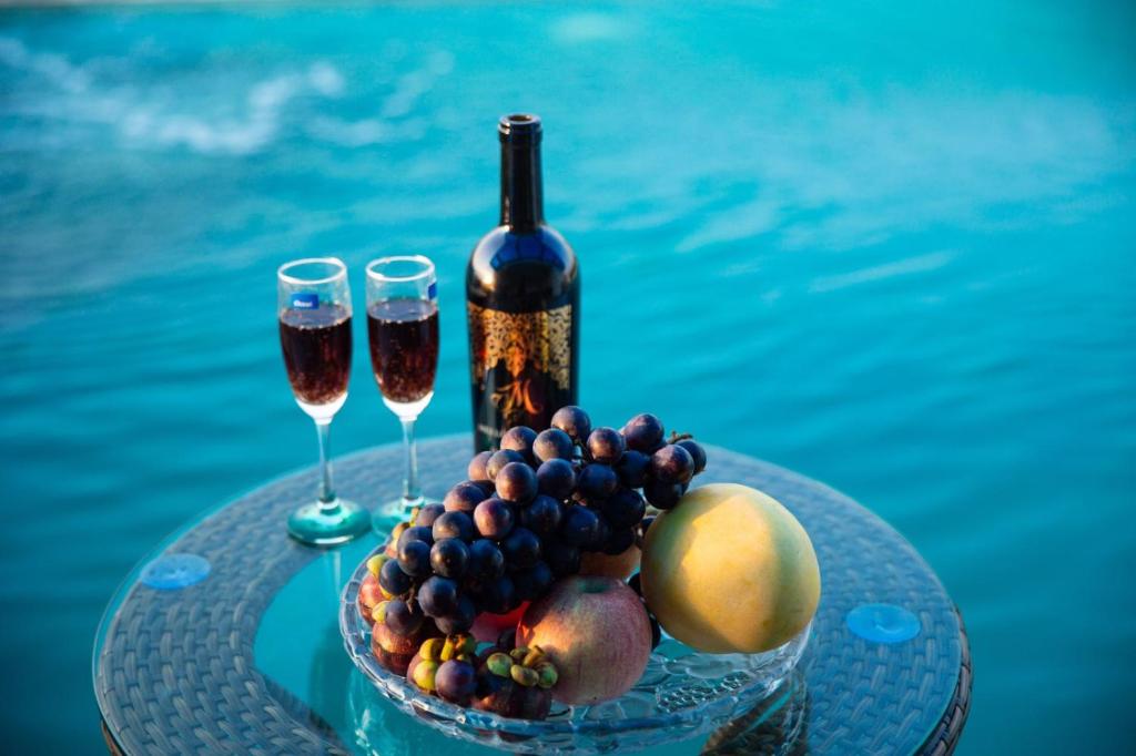 Thanh Hóa的住宿－Bamboo Hotel，一张桌子,上面放着两杯葡萄酒和一碗水果