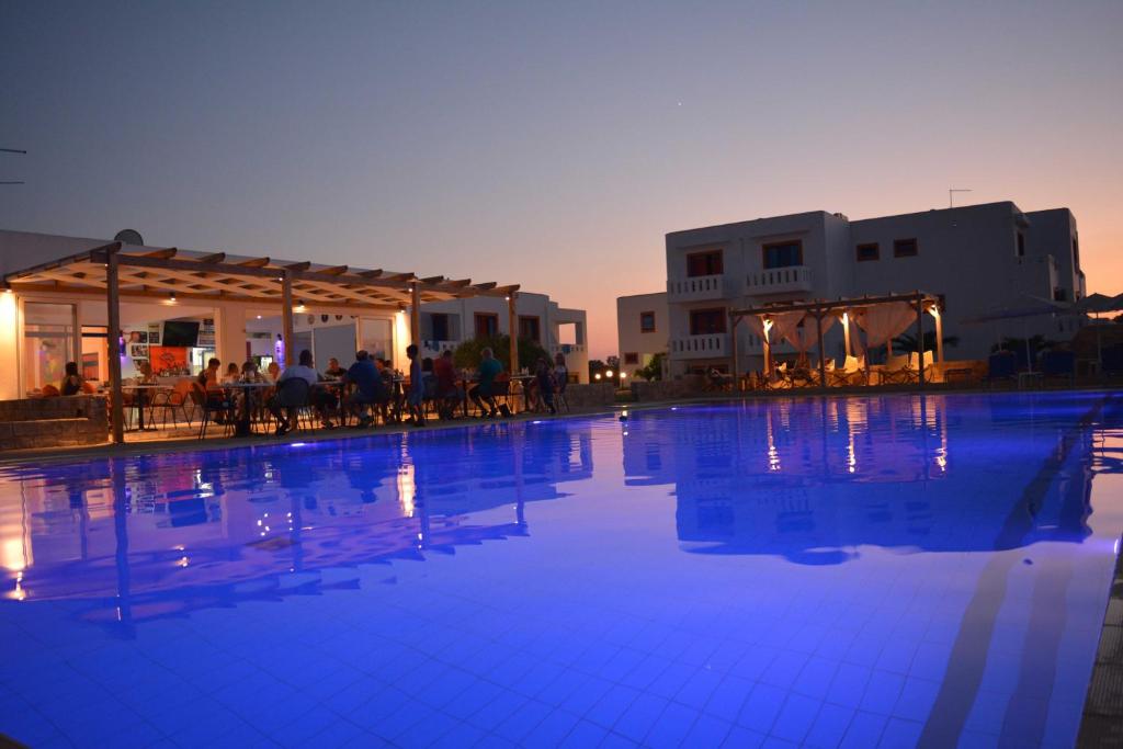 a large swimming pool with blue water in front of buildings at Bouradanis Village Hotel in Marmari