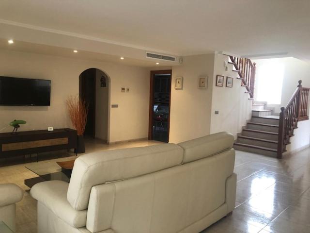 sala de estar con sofá, TV y escaleras en Iberflat Villa Tramontana, en Benicàssim