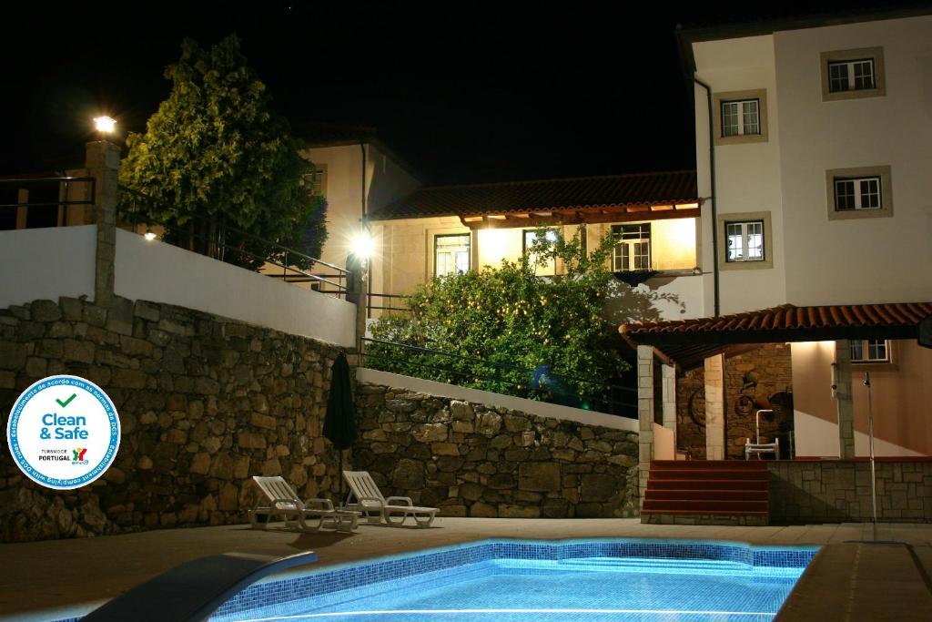 a swimming pool in front of a house at night at Quinta das Murtinheiras in Lamego