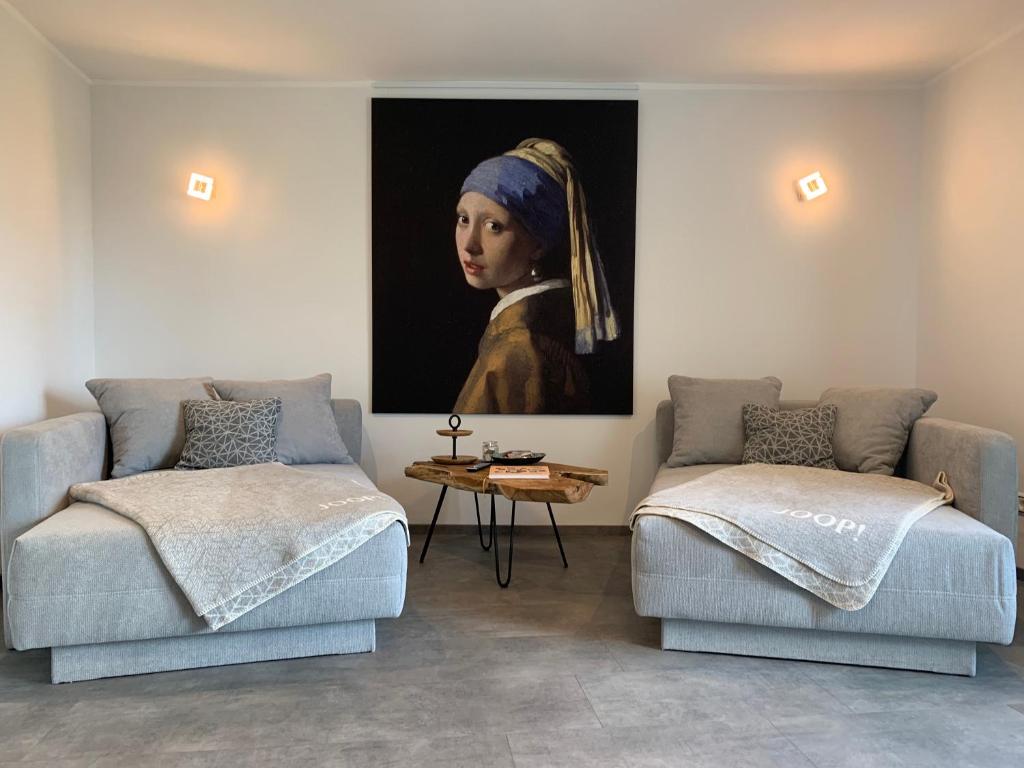 a room with two couches and a painting of a woman at Zeit in Hambach in Neustadt an der Weinstraße
