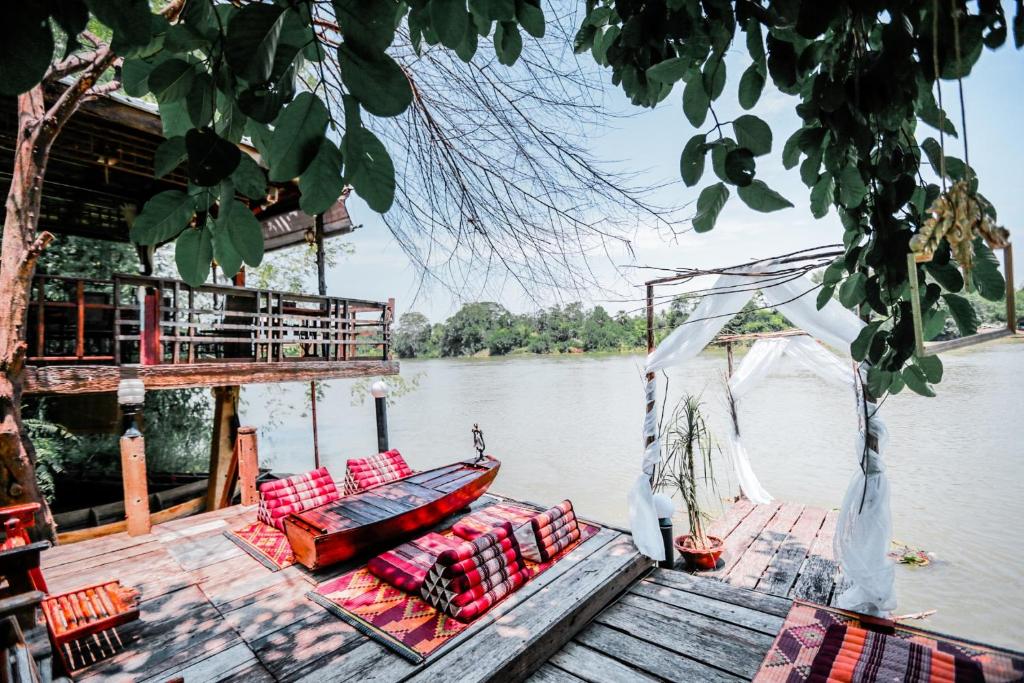 uma doca com cadeiras e um barco na água em The Antique Riverside Resort em Ban Pong