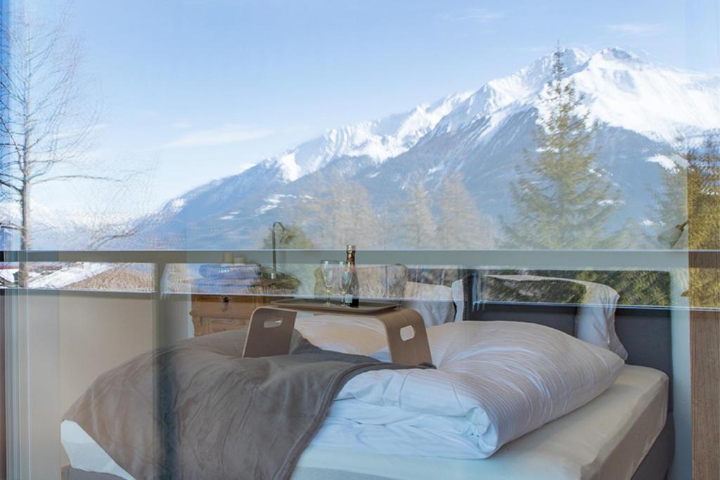 a bed in front of a window with a snow covered mountain at Heislerhof Apartment in Mösern