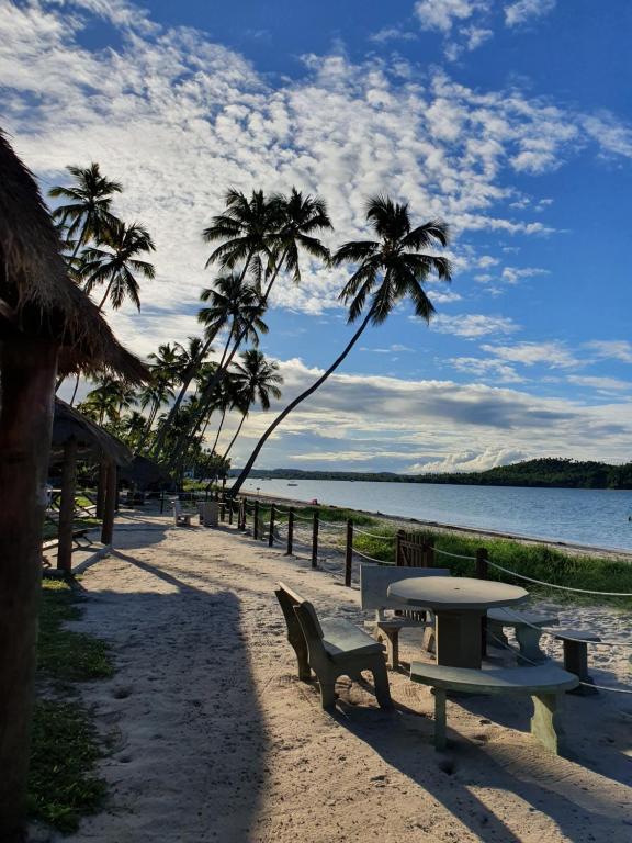 un tavolo e sedie su una spiaggia con palme di Sítio Recanto Feliz - Pertinho da Igrejinha a Praia dos Carneiros