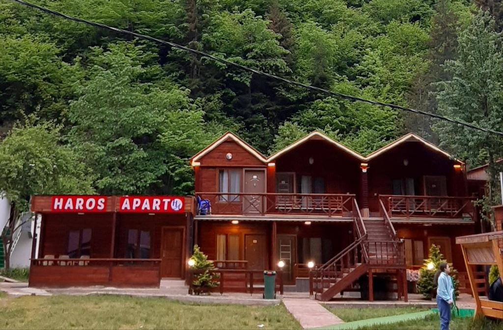 a cabin in the woods with a man standing in front of it at Haros Apart Hotel in Uzungöl