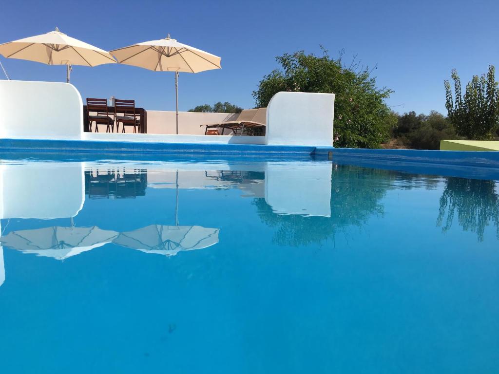 a swimming pool with blue water and umbrellas at Quinta David in Alvor